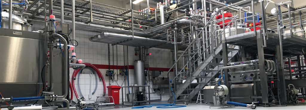 Herstellungsanlage Herstellungsanlage in Produktionshalle, links ein Behälter zur Mayonnaise-Herstellung, rechts befindet sich eine Bühne mit 2 Ansatztanks zur Herstellung von Ketchup, Grillsoßen oder Ähnlichem.